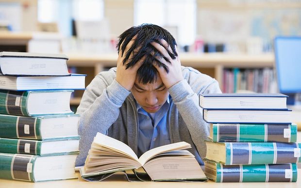 Photo of someone studying behind piles of books