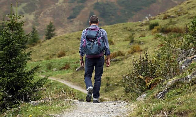 Photo of a man walking on a path in the mountain, taken from behind. The DDD Event Storming opens up a lot of opportunities and is just the beginning of the path.