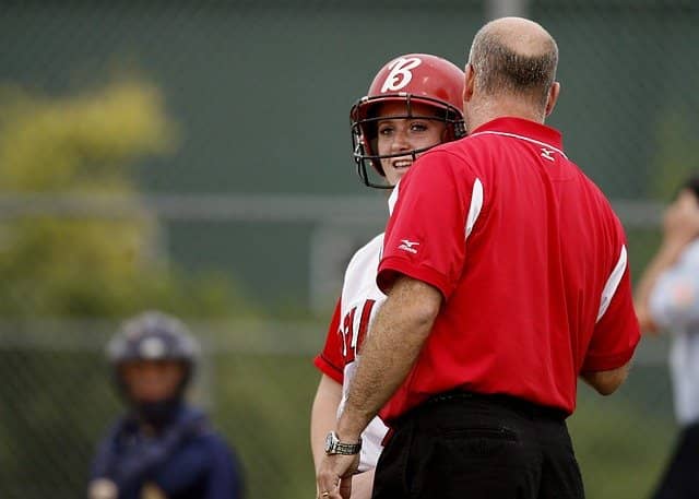 A photo of a softball coach giving advice to a player. Technical Agile Coach is a lot like sports coaching.