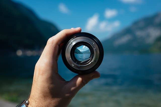 Photo of a lens in front of a landscape. Being able to focus, even in remote work, is key to energized and sustainable work. When coaching a remote team with pair programming, we must show the example and make sure to stay super-focused.