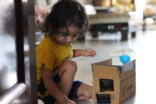 Photo of a young child who just opened a delivery box. Deliveries are like presents. We can share the joy of discovering what's in it for us with our remote pair programming buddy.