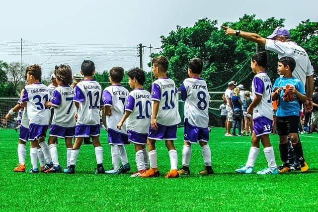 Photograph of a soccer coach with his team of child players. Coaching every team in the traditional way would have been way too long, so we tried something different. In the process, we found a way to make change stick.