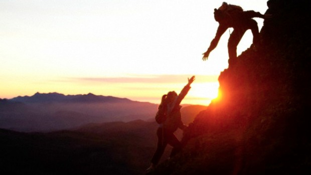 People helping each other to climb a mountain