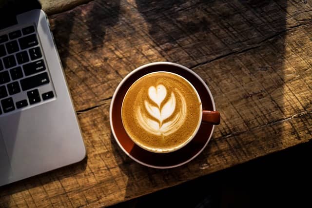 A cup of coffee next to a computer. Developers can pause their large scale refactoring if they work in small enough baby steps