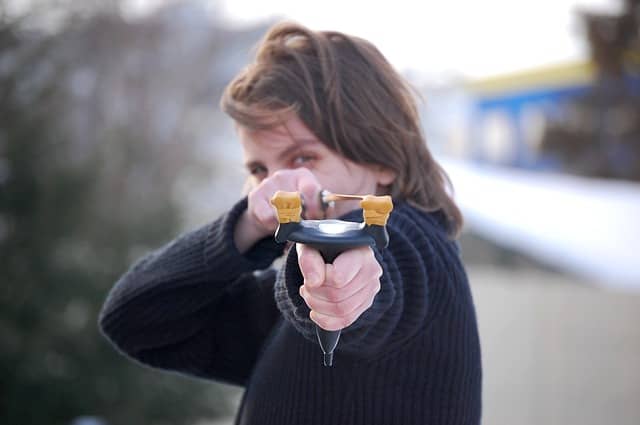 Picture of a girl holding a slingshot. Like a slingshot, early Technical Debt is a great leverage to success when done right, with Evolutionary Architecture, Emergent Design, Event Storming and DDD for example