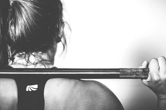 Black and White photo from behind of someone who's holding a weight bar on his shoulders. Instead of wondering 'How to coach a team to TDD, simply using TDD as a workout exercise helps everyone to get over any prior misunderstanding about TDD.