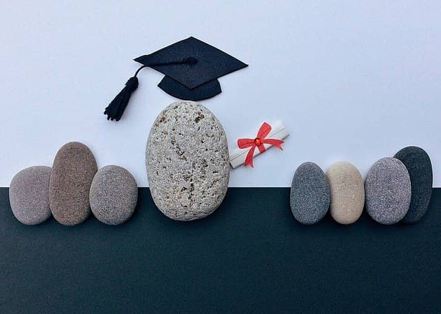 Picture made up of small stones with graduation hats. AWS certifications can be a good learning path to get a team up to speed with serverless.