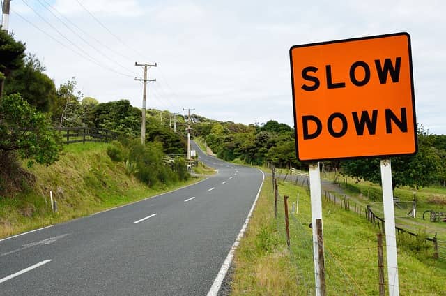 Photo of a road with a road sign written "Slow Down". Slow Driving in the Mob is a very easy and free way to inject some slow in your day.